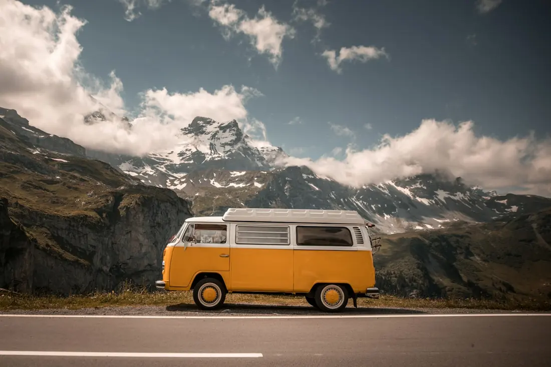 Furgoneta camper amarilla frente a una cordillera